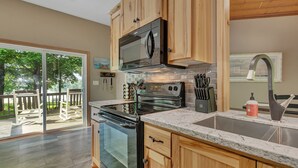 A modern kitchen with wooden cabinets, a stainless steel microwave, a built-in oven, and a granite countertop.