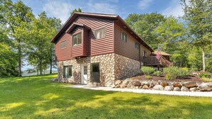 A log cabin with a stone foundation, a porch, and an American flag.