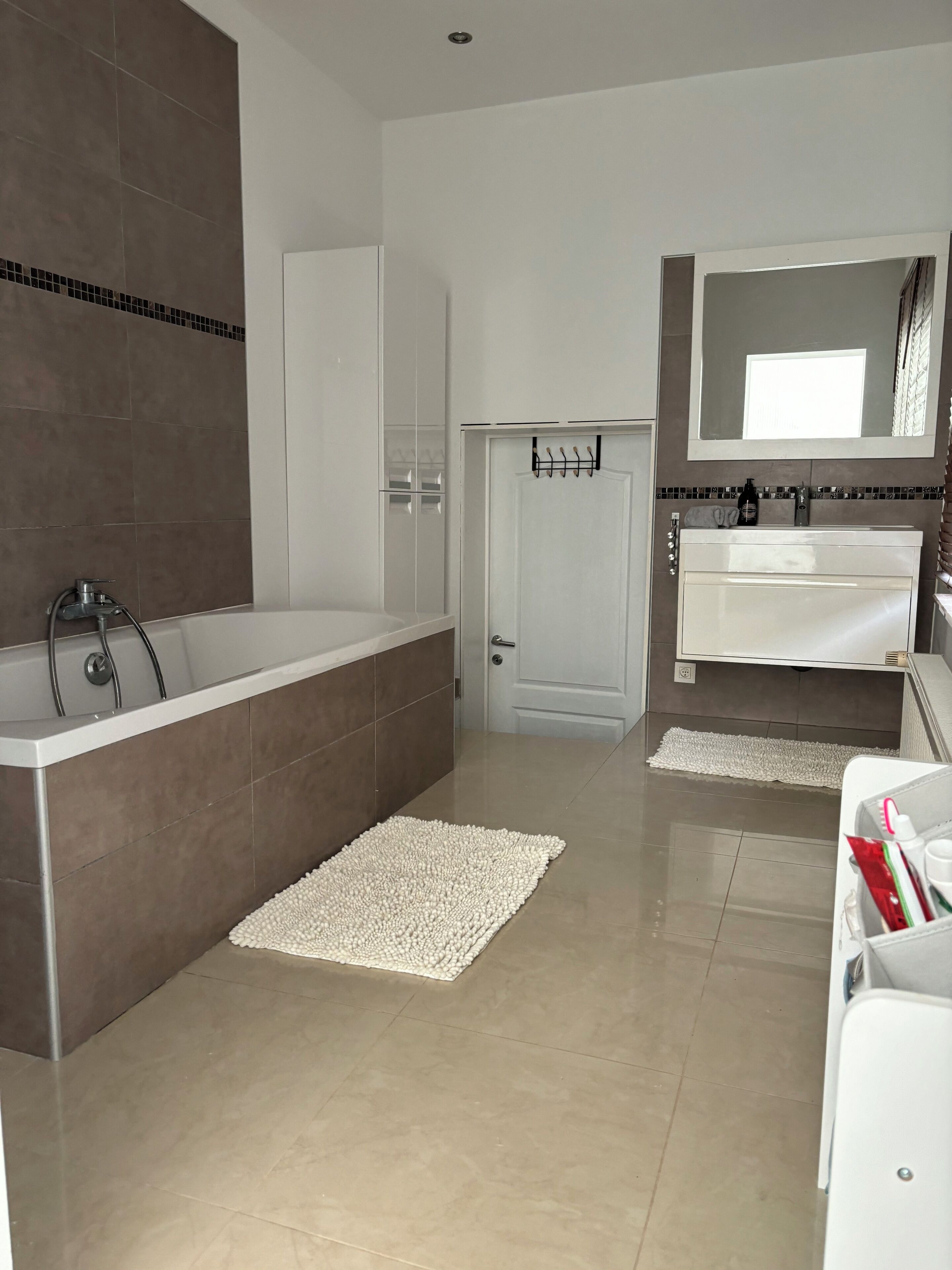 Une salle de bain moderne avec une baignoire, un meuble-lavabo blanc avec un miroir et un espace douche.