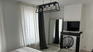 A modern hotel room with a bed, a desk, a chair, a TV, and a large mirror. - MAISON UNIFAMILIALE (Brussels)