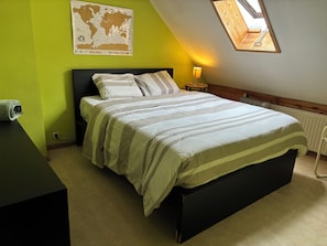 Een slaapkamer met een bed, een wereldkaart aan de muur, een lamp en een dakraam.