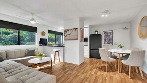 A modern, open-plan living space with a kitchen, dining area, and seating area. - Lovely 2 bedroom ground floor apartment in Noosa Heads with generous private courtyard. (Noosa Heads)
