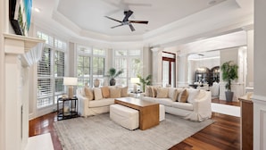 A spacious living room with a large sectional sofa, a wooden coffee table, and a ceiling fan.