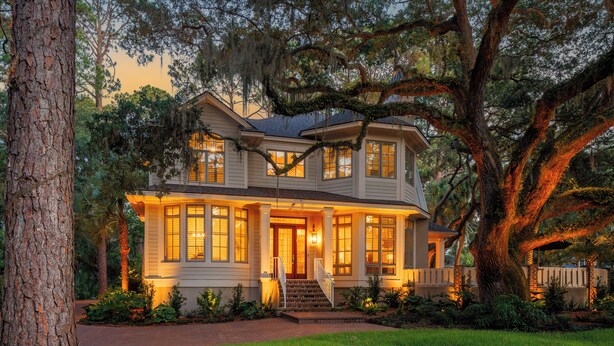 A two-story house with a front porch, large windows, and a well-maintained lawn.