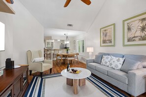 Una sala de estar con sofá, mesa de centro y una zona de comedor con sillas y una mesa.
