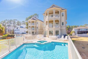 A multi-story hotel with a pool area, including lounge chairs and a hot tub.