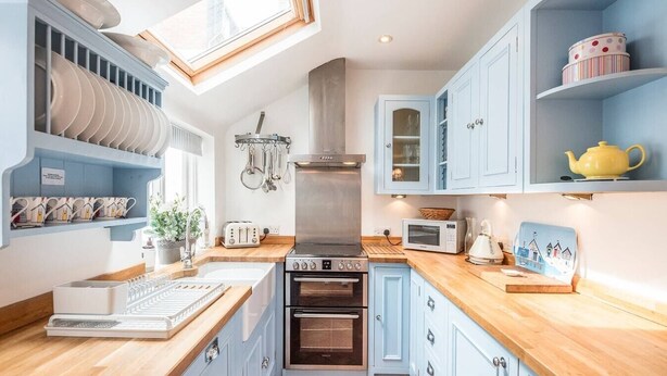 Une cuisine avec des meubles de rangement bleus, une cuisinière, un four à micro-ondes et un grille-pain.