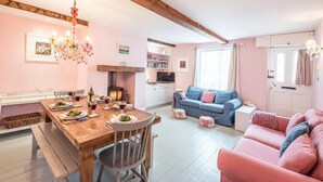 Un salon chaleureux avec une table à manger en bois, dressée pour le repas, un canapé bleu et un divan rose.