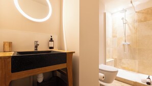 A bathroom with a wooden vanity, a black sink, a mirror with a light, a toilet, and a shower area. - Superb Bordeaux flat in hypercentre for *4 people* (Bordeaux)
