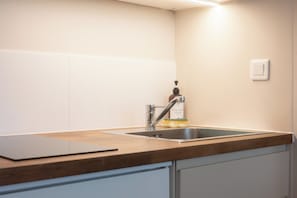Una cucina con un lavello in acciaio inox, un piano di lavoro in legno e una bottiglia di detersivo per piatti.