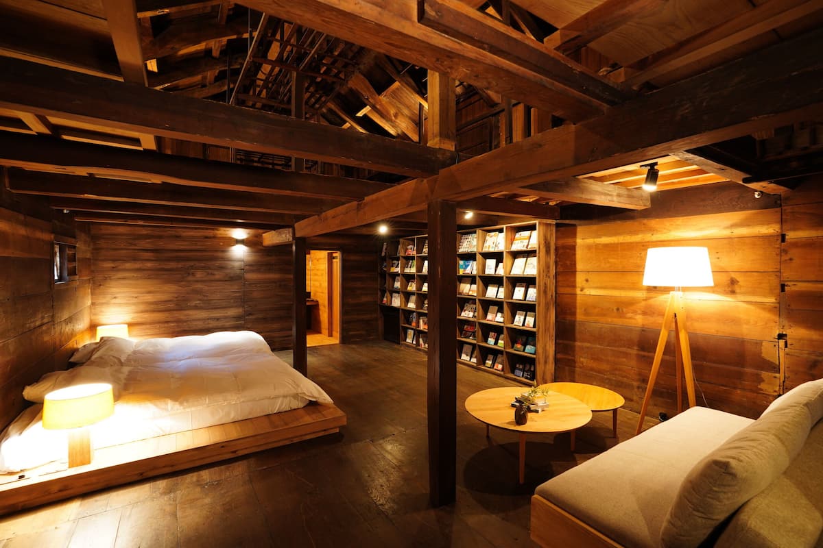 Ein gemütlicher Holzraum mit einem Bett, einem kleinen Tisch und einem Bücherregal.