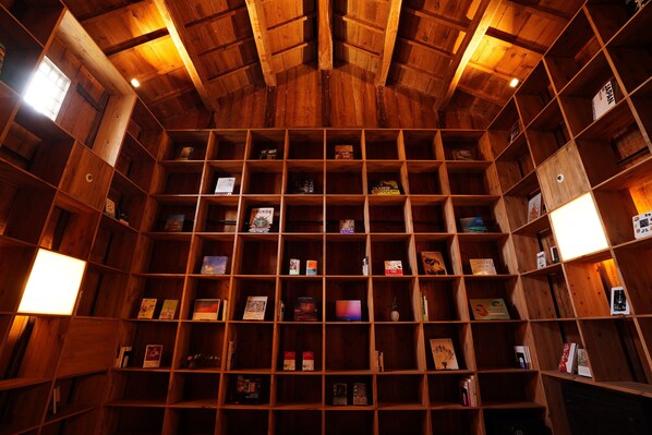 A wooden bookshelf with multiple shelves filled with books and decorative items. - NIPPONIA HARIMA FUKUSAKI ZOUSHONO YAKATA (Fukusaki)