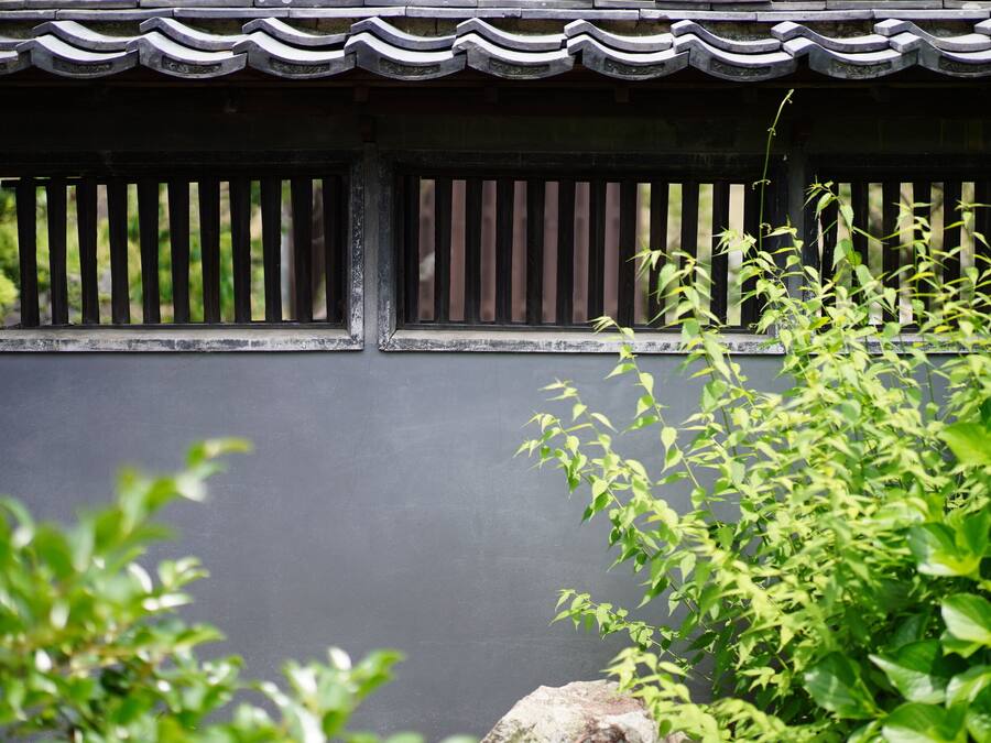 A traditional building facade with a dark wall and a tiled roof.