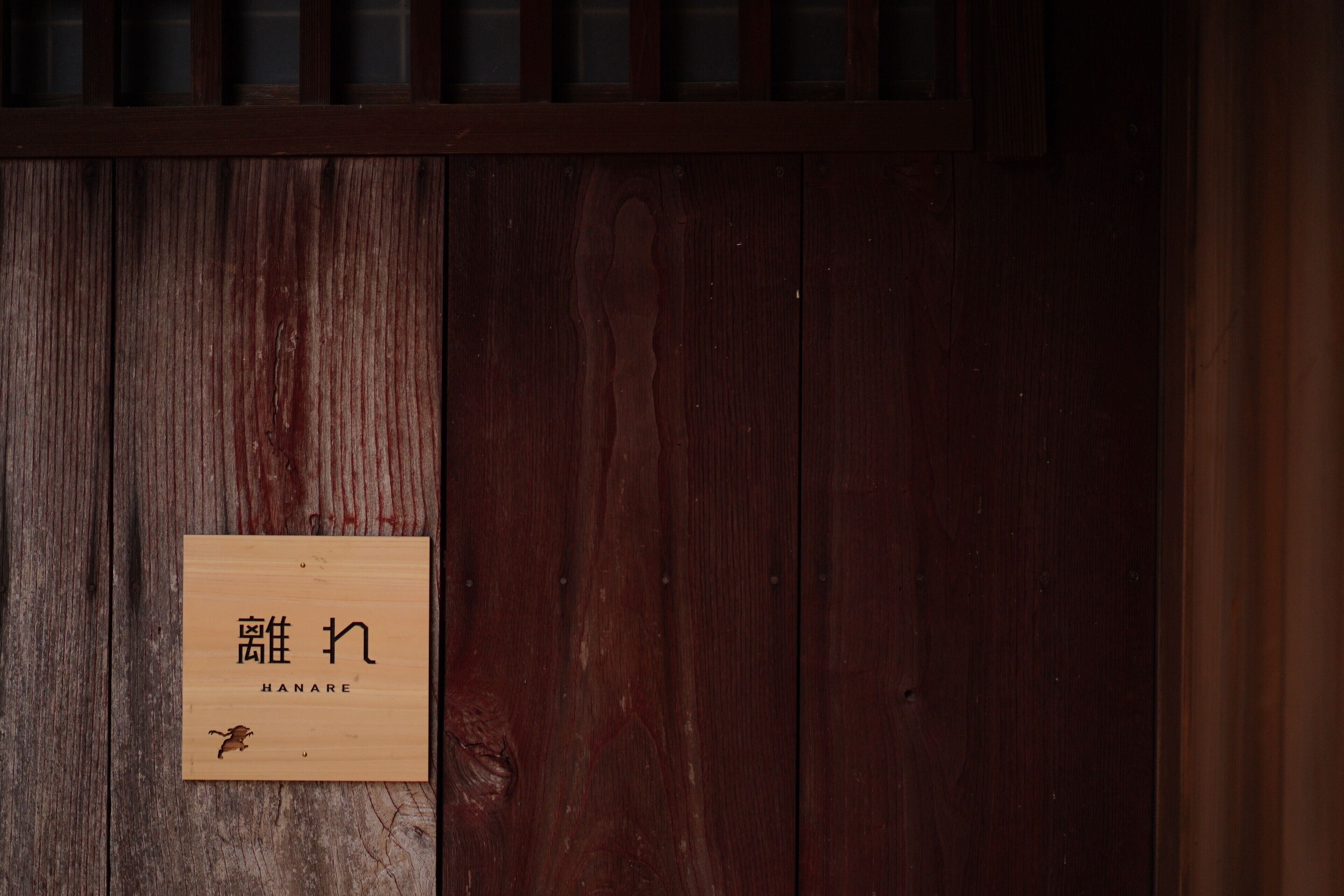 A wooden door with a sign that reads "HANARE" and a small logo.