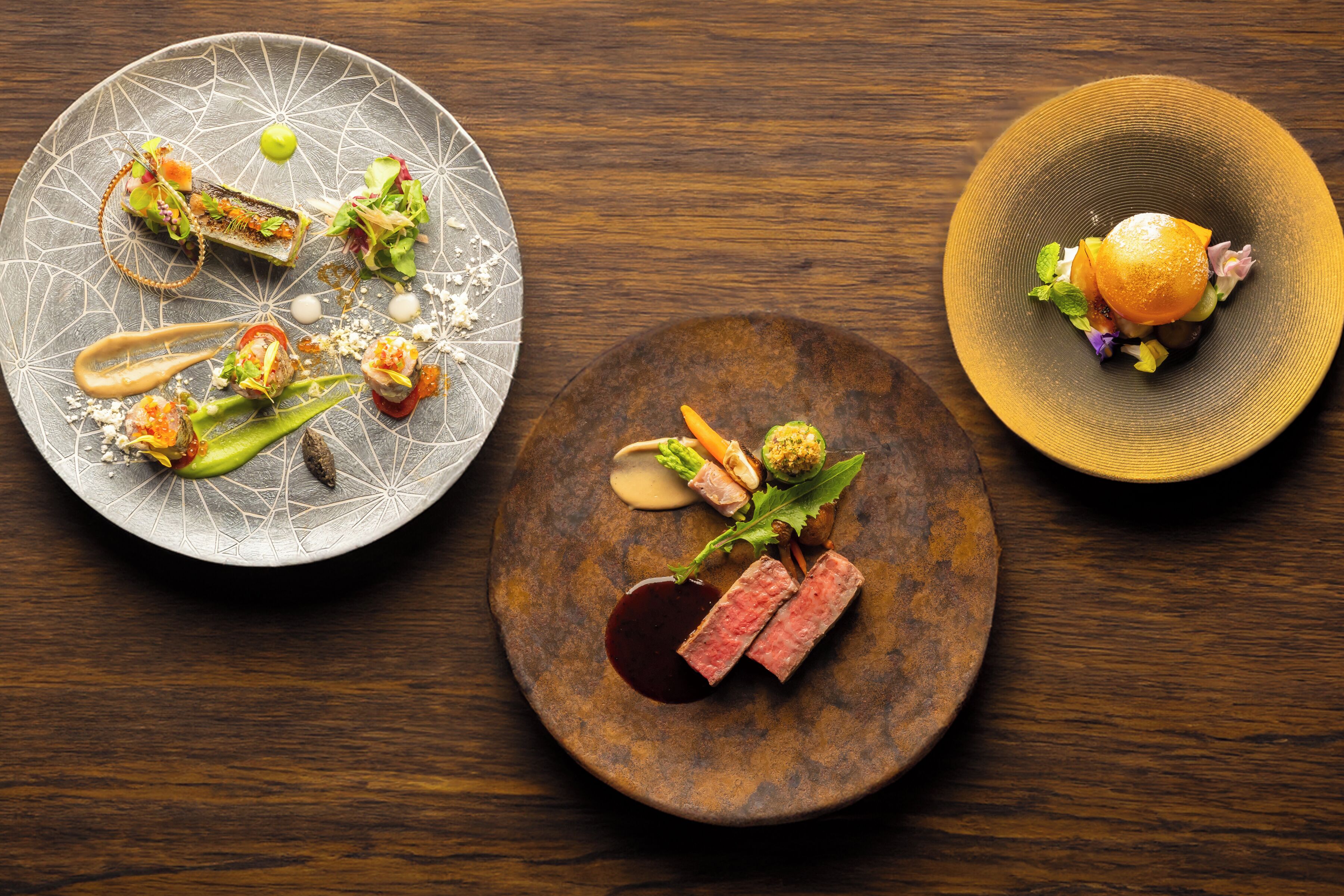 Three plates of food on a wooden table.
