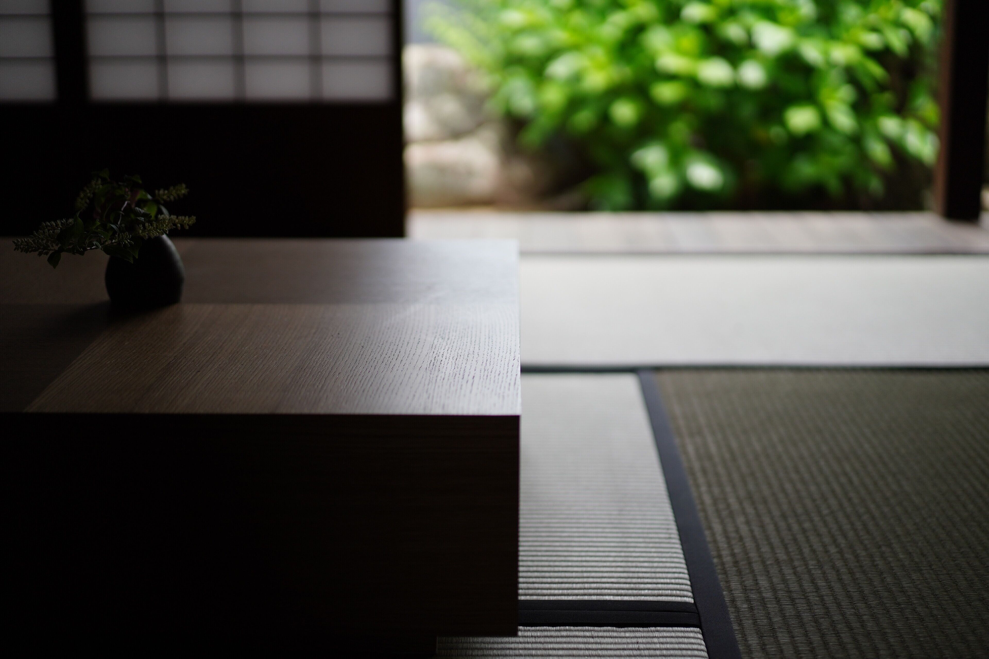 Una habitación con esteras de tatami y una pequeña planta sobre una mesa.