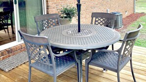 Une terrasse avec une table ronde et quatre chaises, un parasol et un mur en briques.
