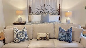 Une chambre à coucher avec un lit, un canapé beige et deux tables de chevet avec des lampes.