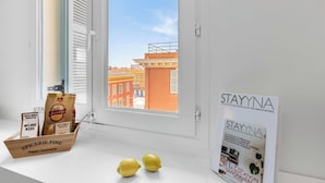 A window with a view of buildings, a sign for Stayyna, a bag of snacks, and two lemons on the windowsill. - Penthouse Massena - 2 bedroom apartment (Nice)
