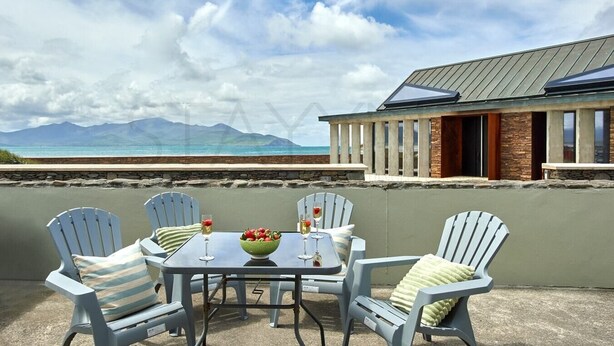 A patio with a table and chairs, overlooking a beach and mountains. - Beachfront Break - 2 bedroom home (County Kerry)