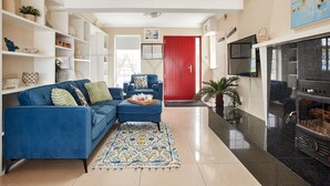 A modern living room with a blue sofa, a fireplace, and a red door. - Beachfront Break - 2 bedroom home (County Kerry)