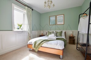 A bedroom with a bed, a window with curtains, a chandelier, and two framed pictures on the wall. - Waterfront Annex one bedroom annex (Dingle)