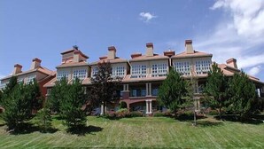 A large, multi-story building with a symmetrical facade, multiple chimneys, and large windows.