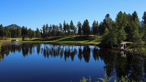 A tranquil lakeside view with a golf course, a small building, and a gazebo. - Comfort Studio - 210B (Kelowna)