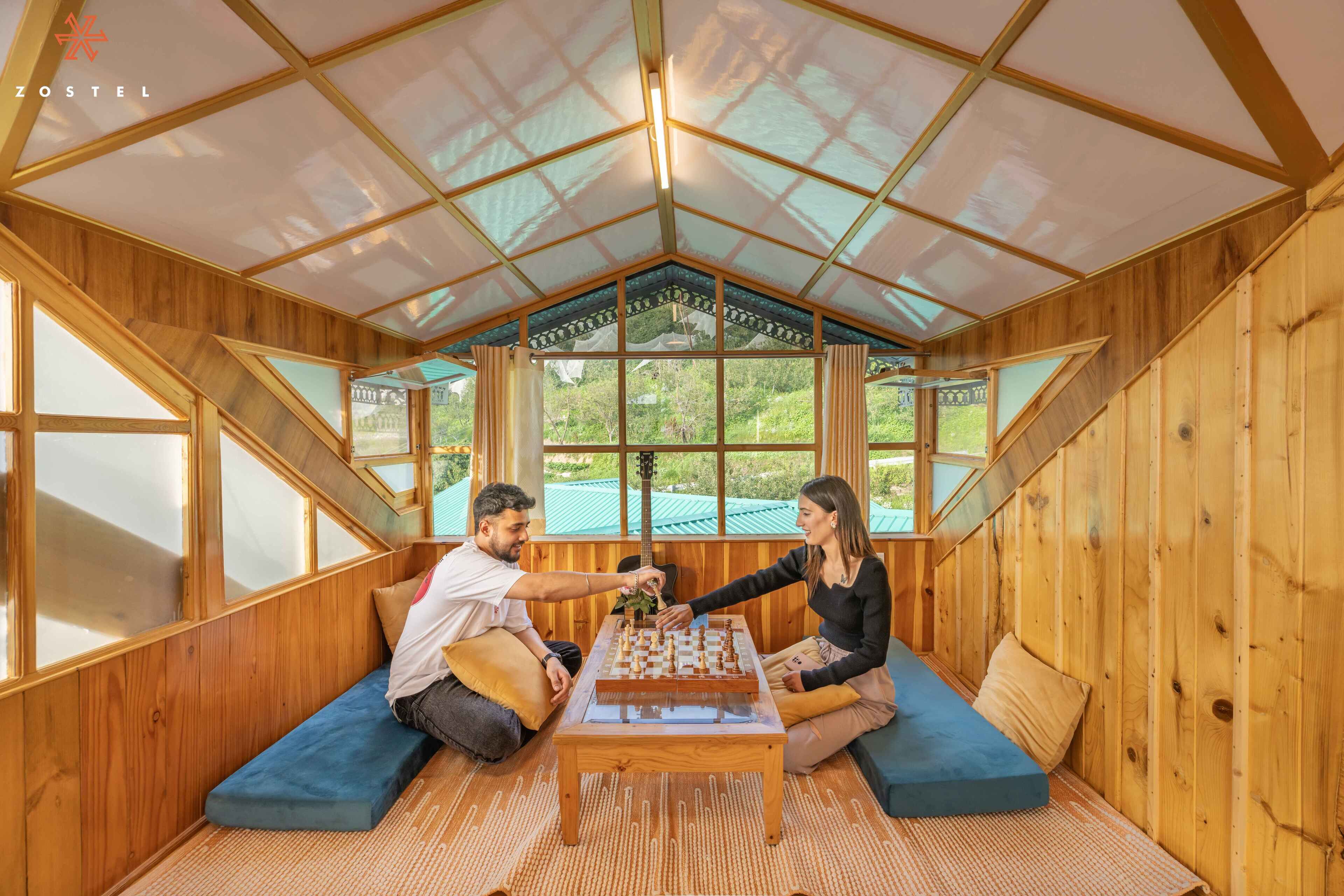 Ein gemütlicher Holzraum mit einem großen Fenster, einem Schachbrett und einer Couch.