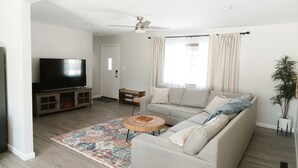 Un salon avec un canapé, un téléviseur et un ventilateur de plafond.