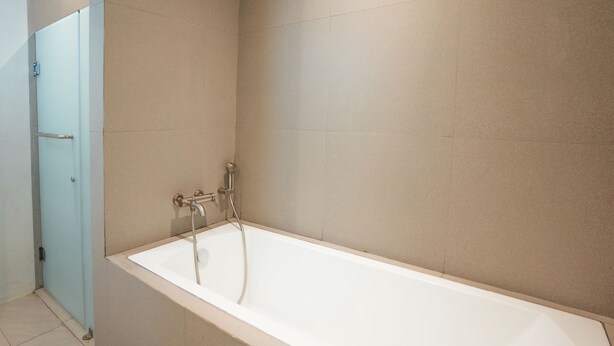 A modern bathroom with a large bathtub, a shower, and a blue door. - Solitude Acacia Resort (Mabini)
