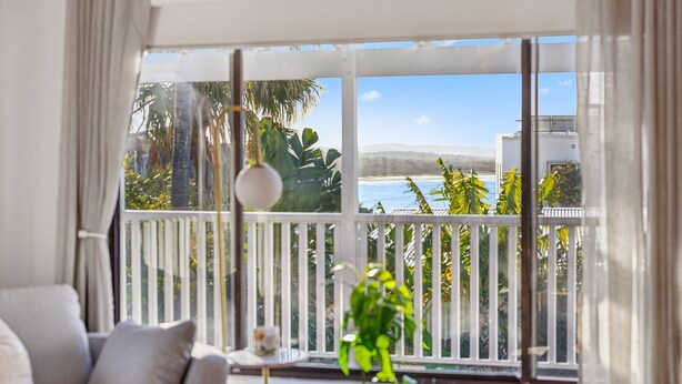 A balcony with a view of the sea and mountains.
