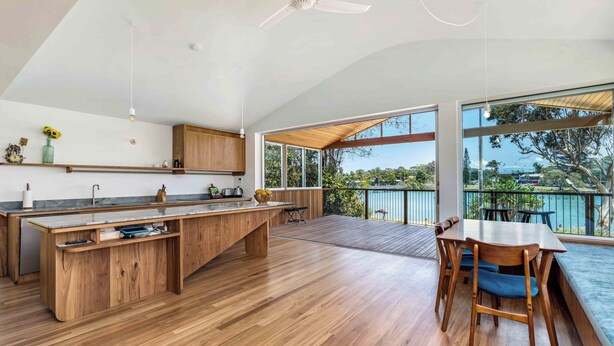 Eine moderne Küche mit Holzschnitzereien, einer großen Kochinsel und einem Essbereich mit Seeblick.