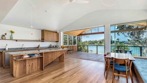 Une cuisine moderne avec des meubles en bois, un grand îlot central et un coin repas offrant une vue sur le lac.