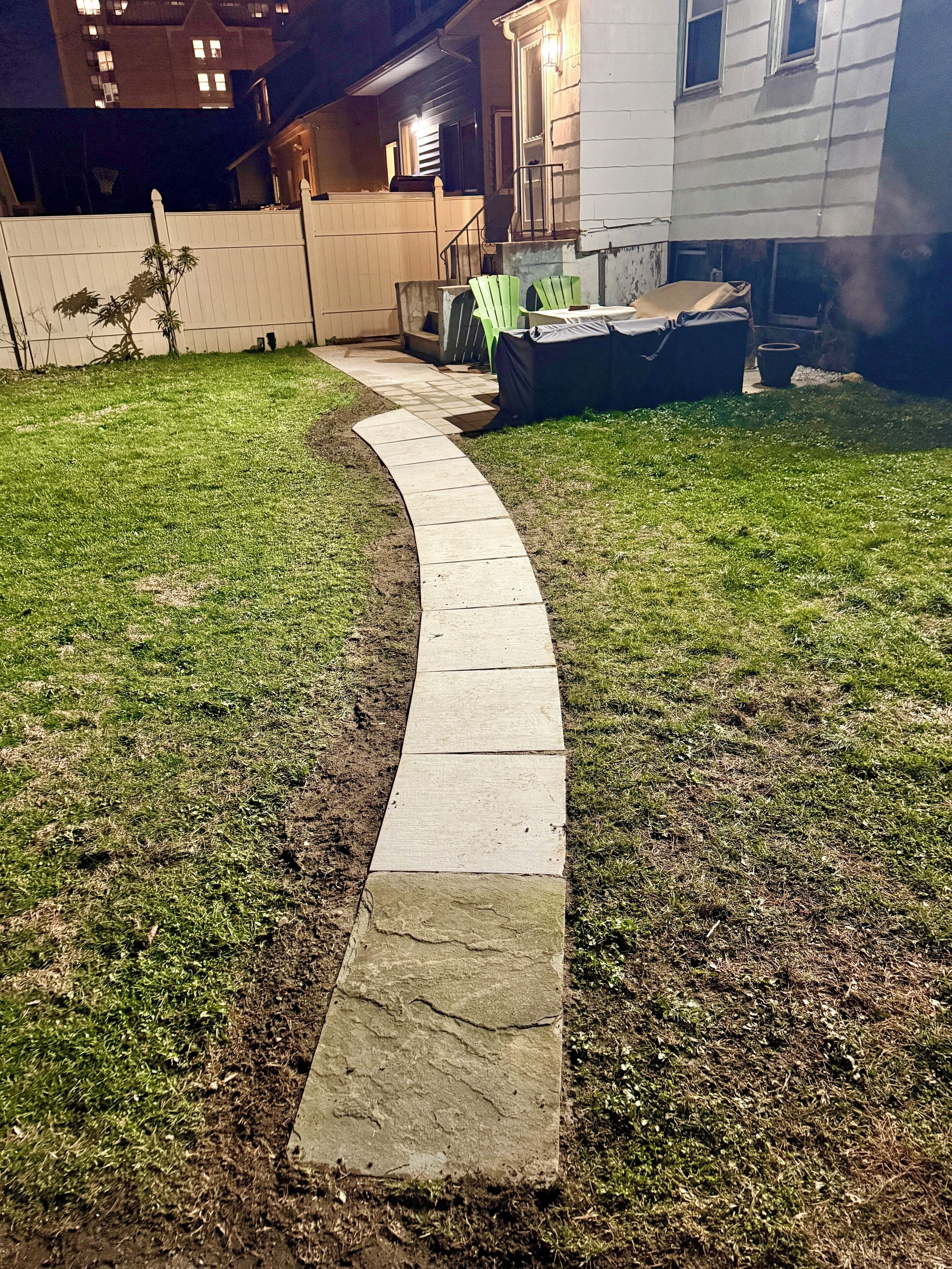 Un chemin pavé mène à une maison dotée d’une cour clôturée.