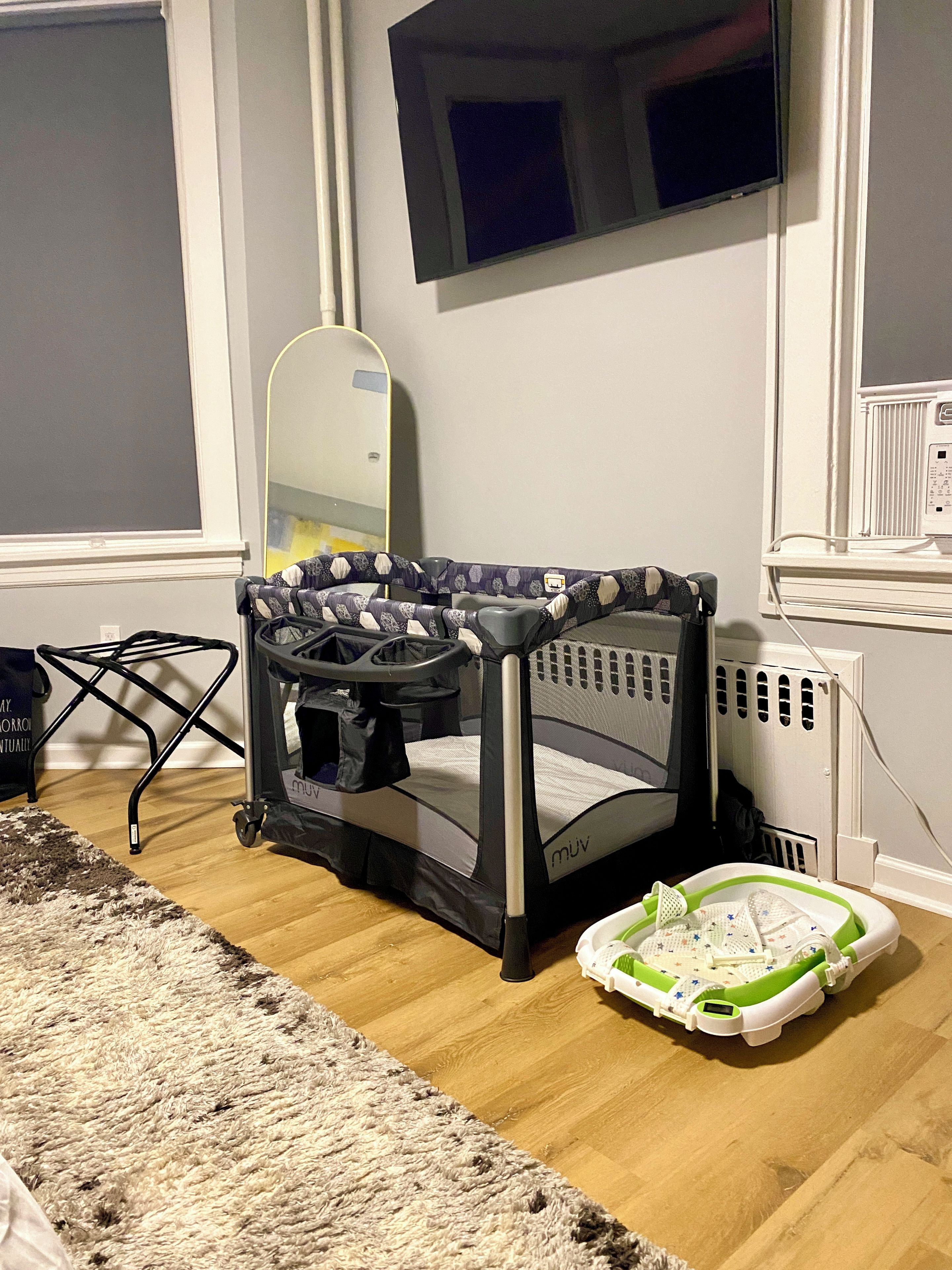 A room with a crib, a walker, and a play mat on the floor.