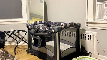 A room with a crib, a walker, and a play mat on the floor.
