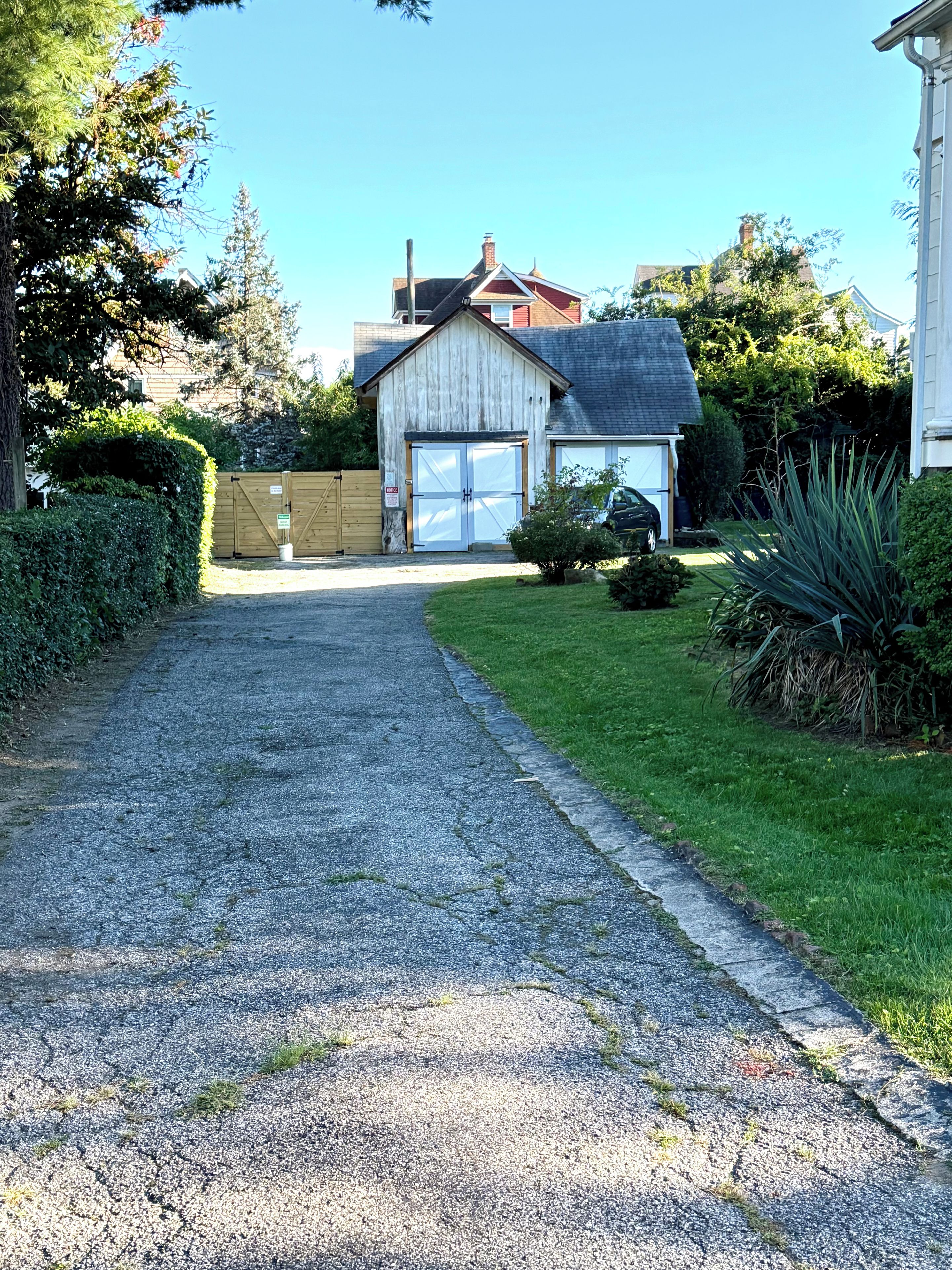 A gravel driveway leading to a wooden garage with a garage door.