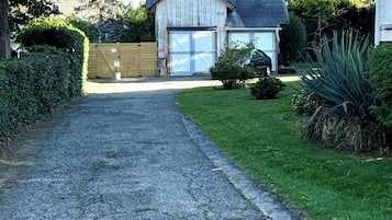 A gravel driveway leading to a wooden garage with a garage door.