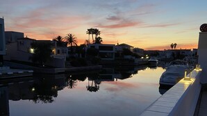 A waterfront hotel with a pool reflecting the sunset, modern architecture, and ambient lighting along the deck. - Pleasant house on the canal with pool (Castelló d'Empúries)