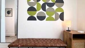 A modern interior with a geometric wall art piece, a mirror, a bench, and a lamp. - Alpine Townhouse - stylish, peaceful, and walking distance to Ellicottville (Ellicottville)
