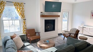 A modern living room with a fireplace, a television, and a seating area with sofas and chairs. - Alpine Townhouse - stylish, peaceful, and walking distance to Ellicottville (Ellicottville)