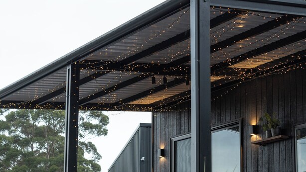 Un bâtiment moderne doté d’une terrasse en bois et illuminé de guirlandes lumineuses.