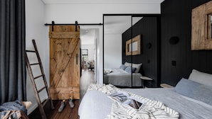 Une chambre moderne avec un grand lit, une porte coulissante en bois et une vue sur une autre pièce.