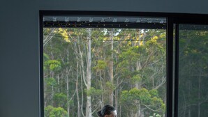 Une pièce dotée d’une grande porte-fenêtre coulissante qui donne sur un espace extérieur comprenant une terrasse en bois et de la verdure.