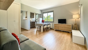 A modern living space with a dining area, kitchen, and a TV on a wooden cabinet. - Sujadaro Refuge (Osséja)