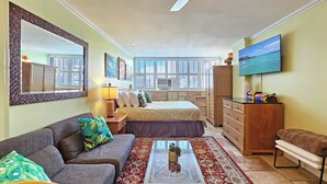 Una habitación luminosa con cama, sofá, mesa de centro y televisor.