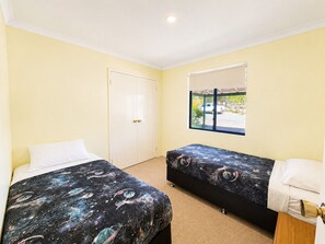 A room with two beds, a window with a view of a parked car, and a door. - Meelup Ridge (Dunsborough)