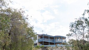 A two-story building with a balcony, surrounded by trees and a rocky area. - Meelup Ridge (Dunsborough)