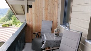 A balcony with a table and two chairs, a window, and a view of the landscape. - Holiday flat ‘Grabmeier - Number 2’ with mountain view, balcony and Wi-Fi (Grainet)